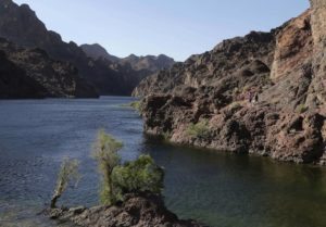 FILE--In this Sunday, April 14, 2013 file photo, hikers make their way along the banks of the Colorado River in Black Canyon south of Hoover Dam, near Willow Beach, Ariz. Decision-makers from seven Western states, Indian tribes and several conservation groups will be meeting in San Diego May 28 to consider their next steps in a collaborative effort to squeeze every useable drop from the overtaxed Colorado River. The meeting comes five months after the Secretary of the Interior declared the river won't be able to meet demands over the next 50 years of a regional population now about 40 million and growing. (AP Photo/Julie Jacobson, File)